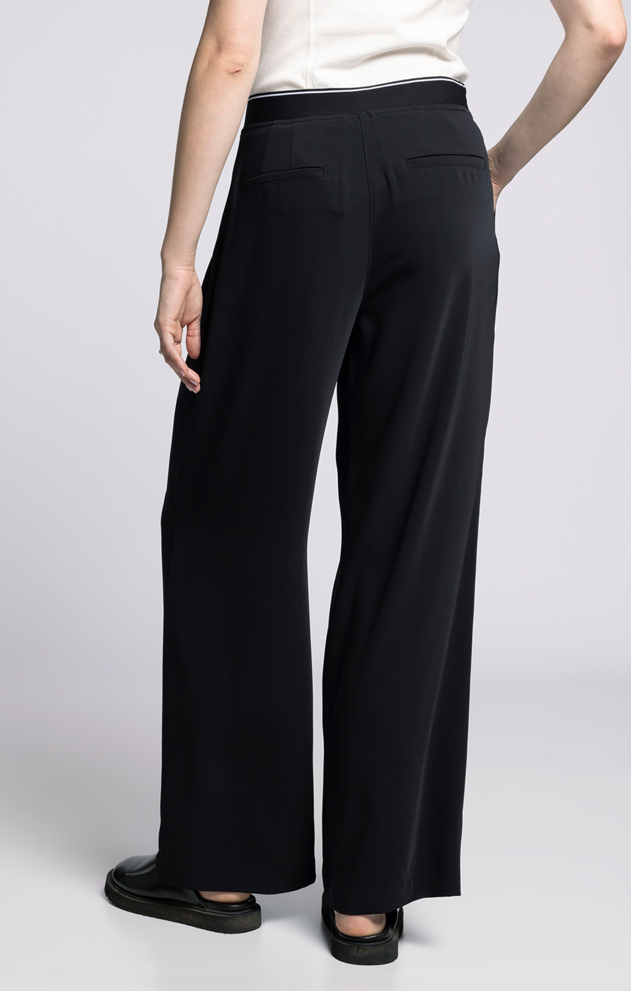 Person wearing black wide-leg pants on a plain background