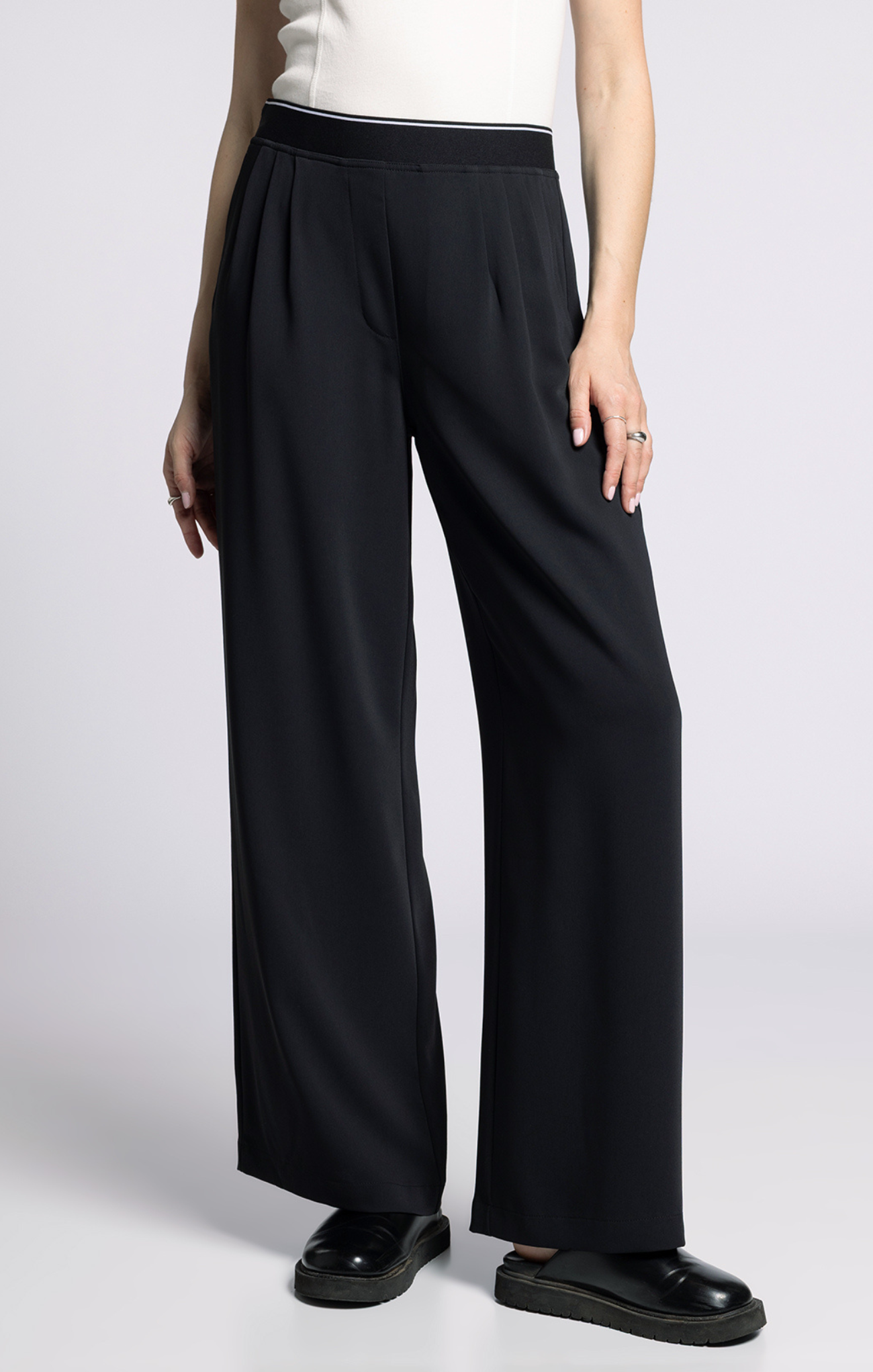 Person wearing black wide-leg pants on a plain background