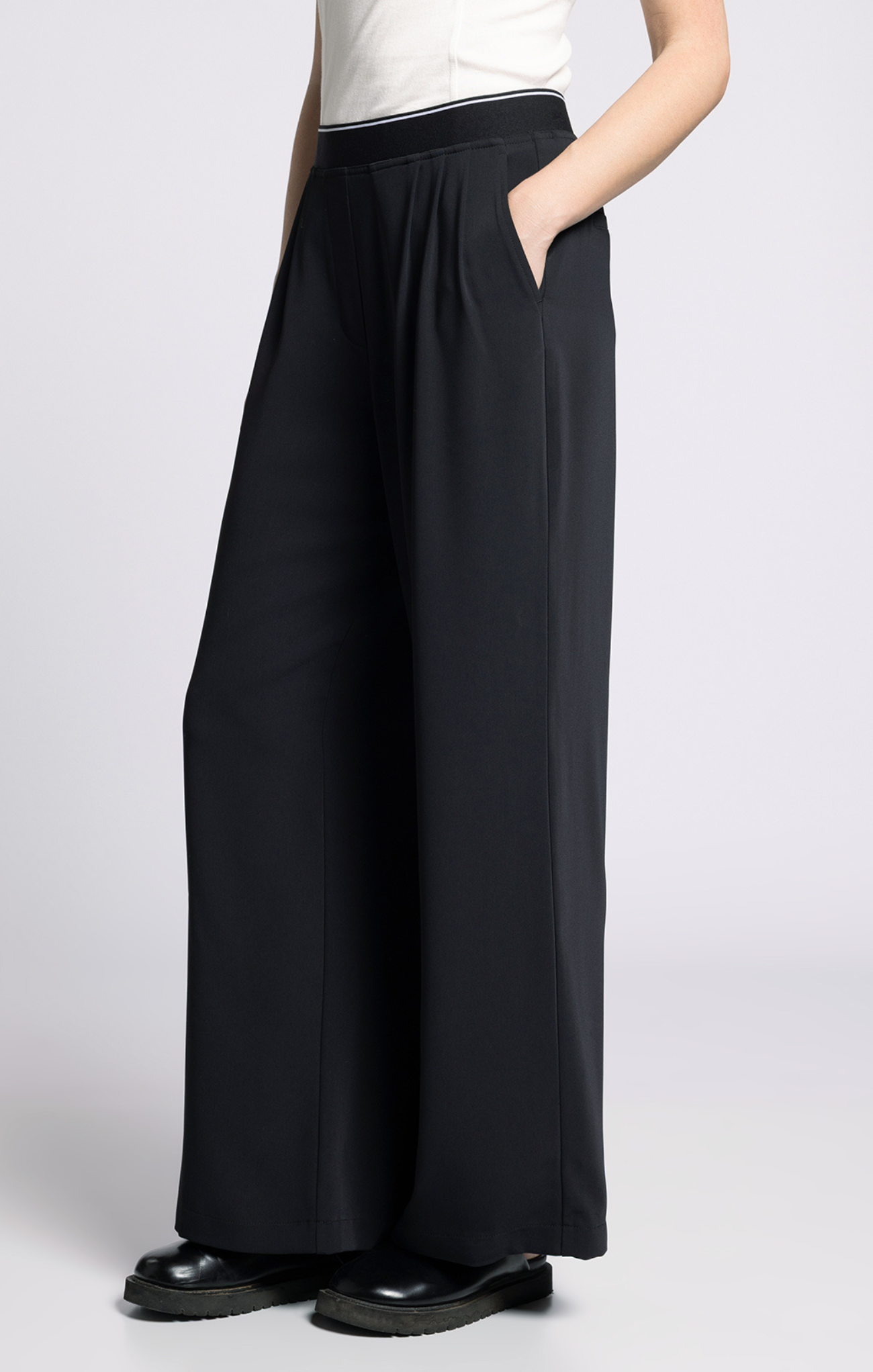 Person wearing black wide-leg pants on a white background