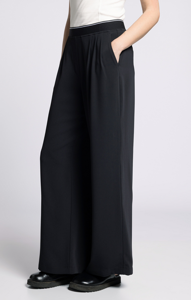 Person wearing black wide-leg pants on a white background