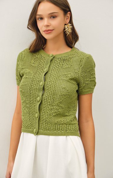 Woman wearing a green knitted cardigan against a plain background