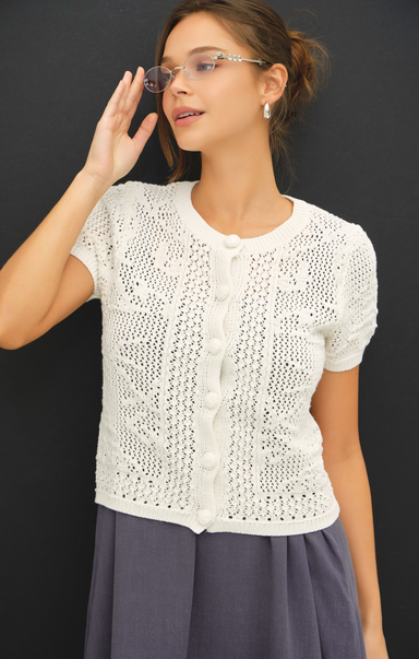 Woman wearing a white lace top and glasses against a black background