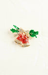 Decorative brooch with red berries and green leaves on a white background