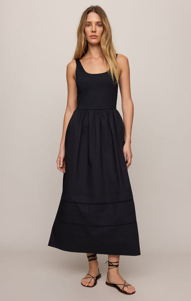 Woman wearing a black sleeveless dress against a plain background