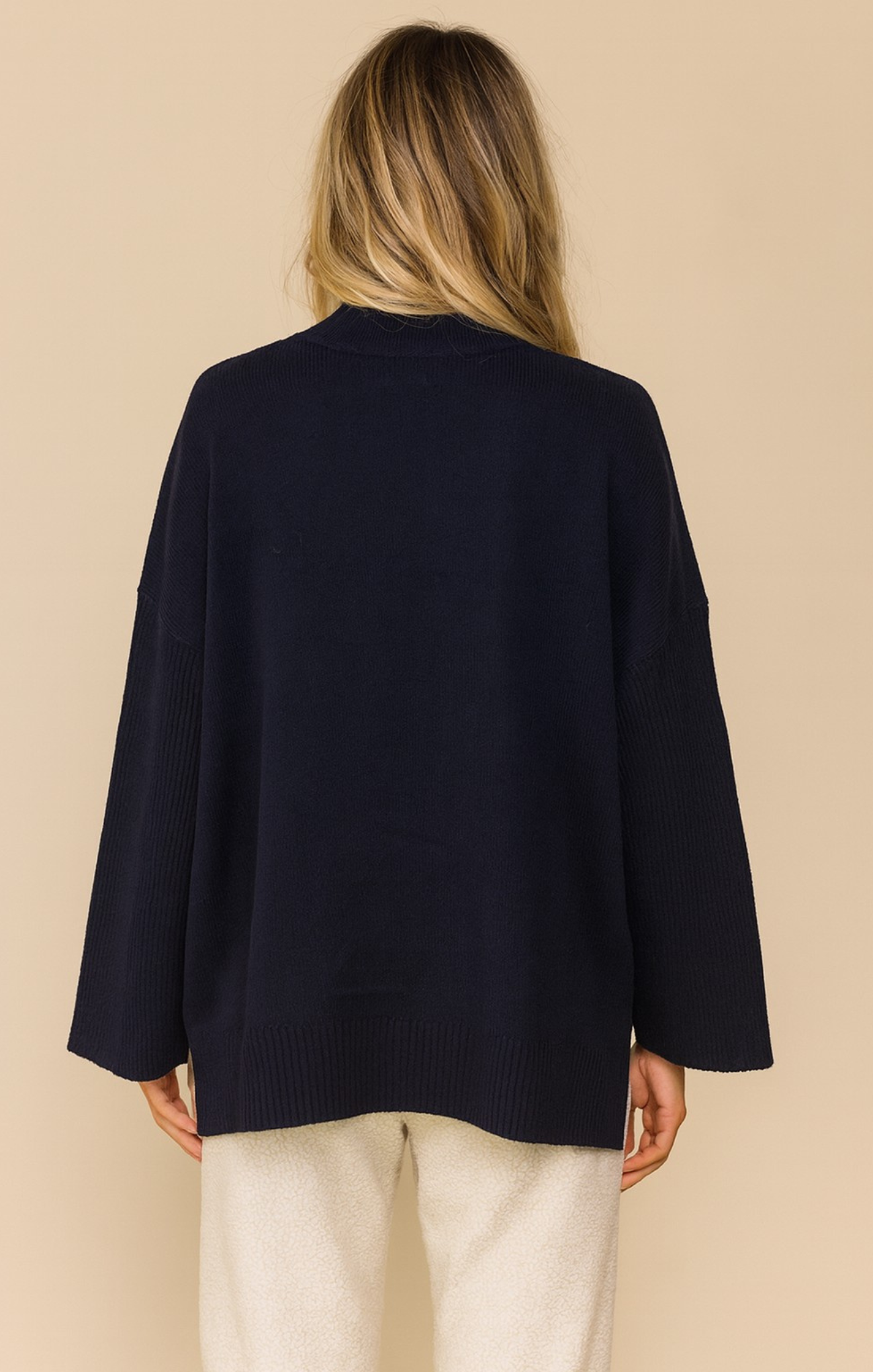 Person wearing a navy blue cardigan on a beige background