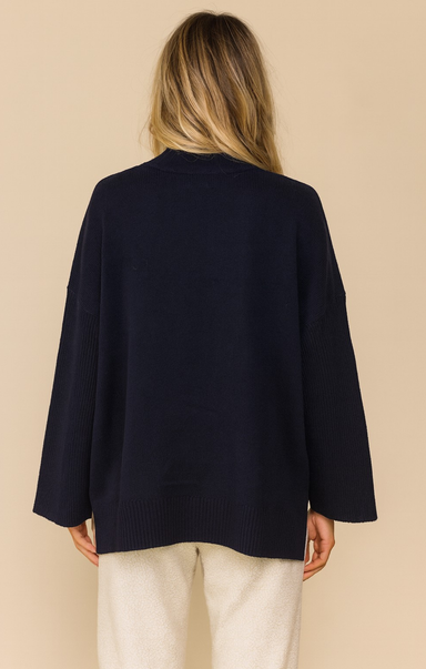 Person wearing a navy blue cardigan on a beige background