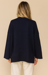 Person wearing a navy blue cardigan on a beige background