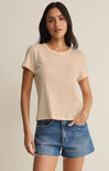 Woman wearing a beige t-shirt and denim shorts on a plain background