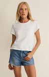 Woman wearing a white t-shirt and denim shorts on a beige background