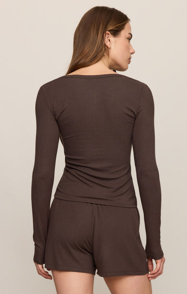 Woman wearing a brown long-sleeve top and shorts set on a beige background
