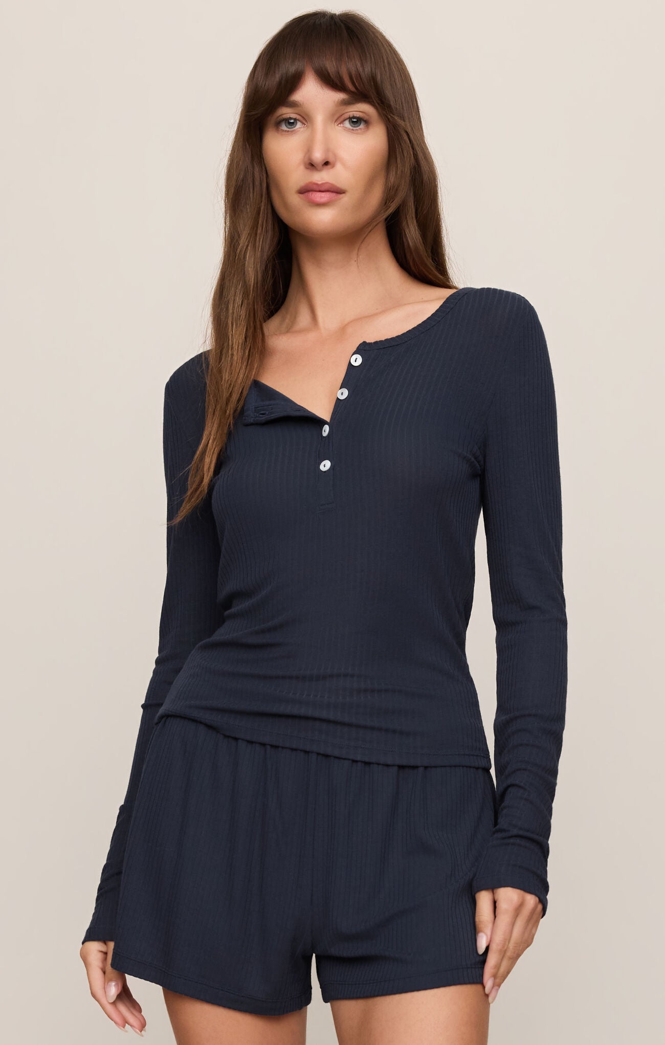Woman wearing a navy blue long-sleeve top and shorts set on a beige background