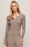 Woman wearing a brown long-sleeve top and pants on a beige background