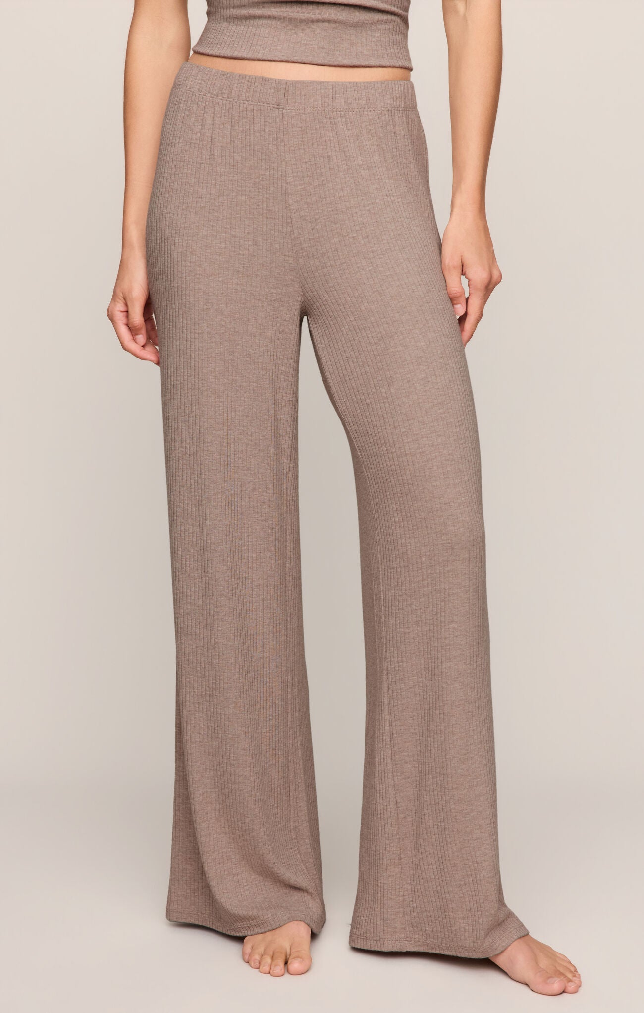 Person wearing brown ribbed pants on a plain background
