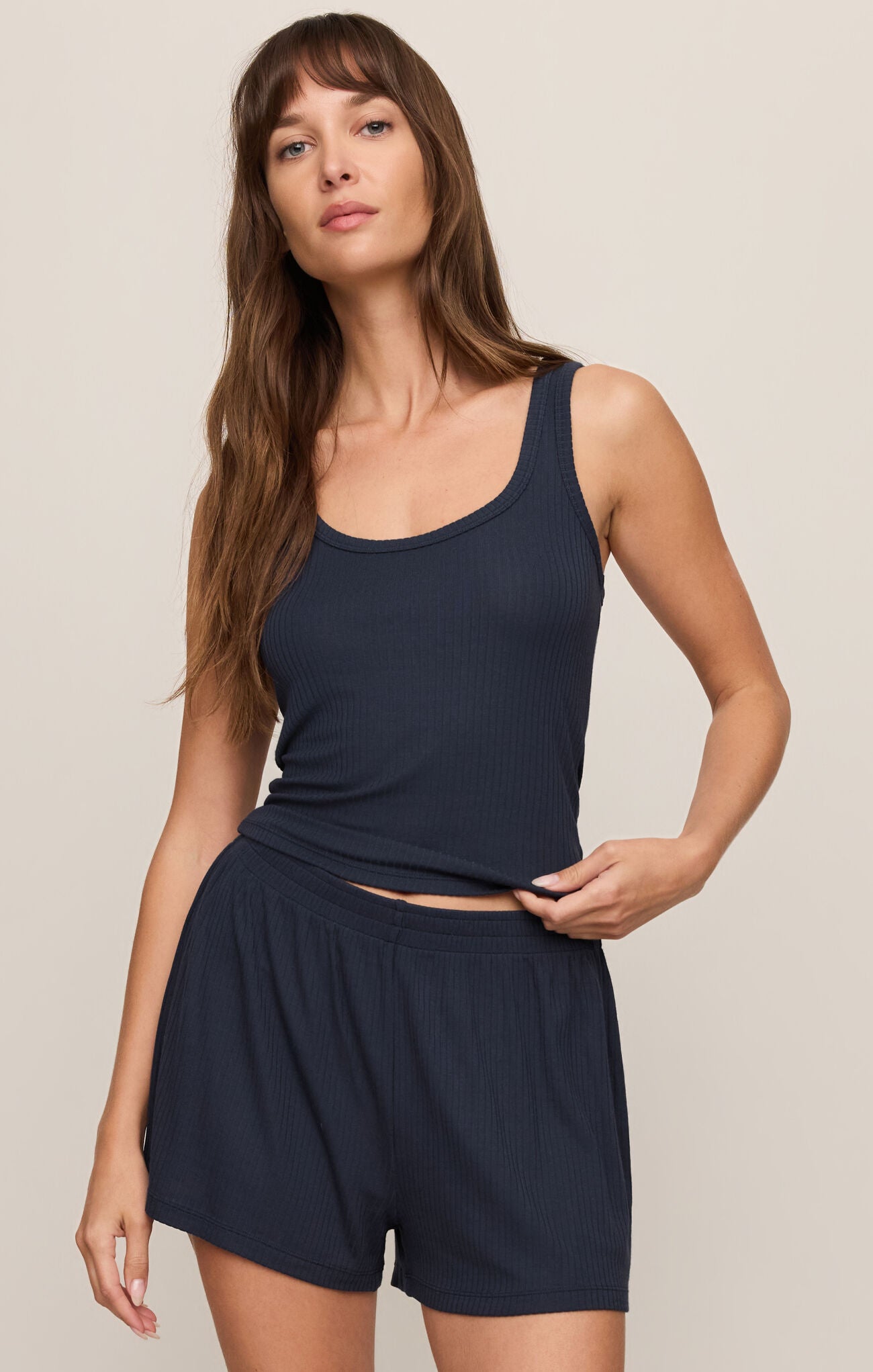 Woman wearing a navy blue tank top and shorts set on a beige background