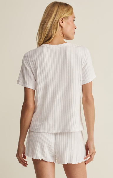 Woman wearing a white ribbed t-shirt and shorts set on a beige background