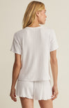 Woman wearing a white ribbed t-shirt and shorts set on a beige background