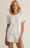 Woman wearing a white ribbed top and shorts set on a beige background