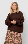 Woman wearing a brown sweater and floral skirt on a white background