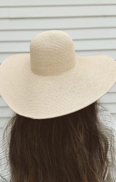 Beige straw hat worn by a person with long hair against a neutral background