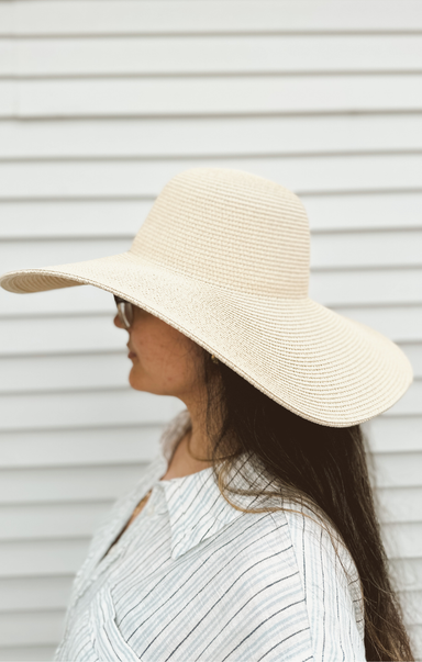 Person wearing a wide-brimmed beige hat against a white background