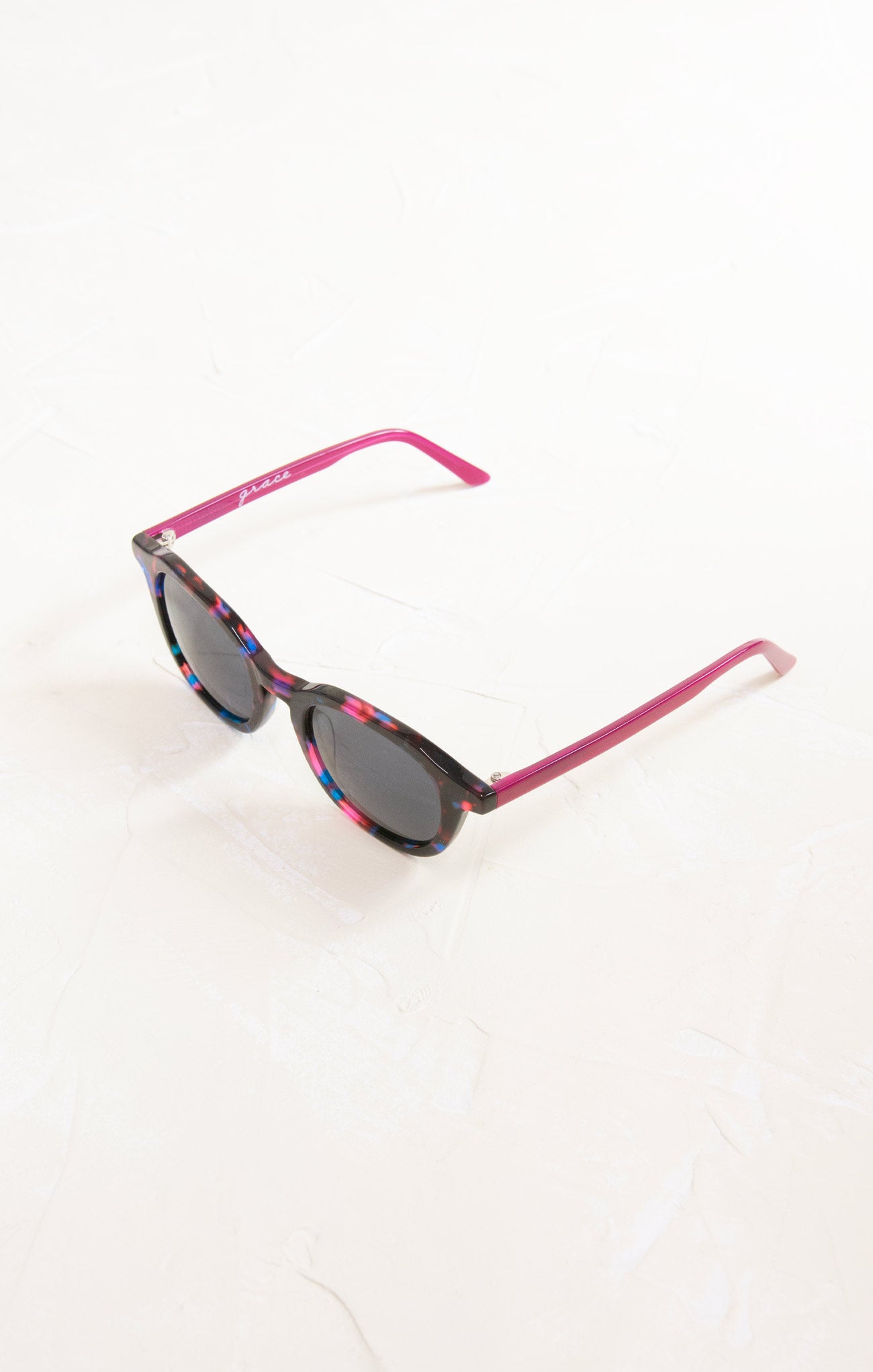 Sunglasses with pink frame and dark lenses on a white background