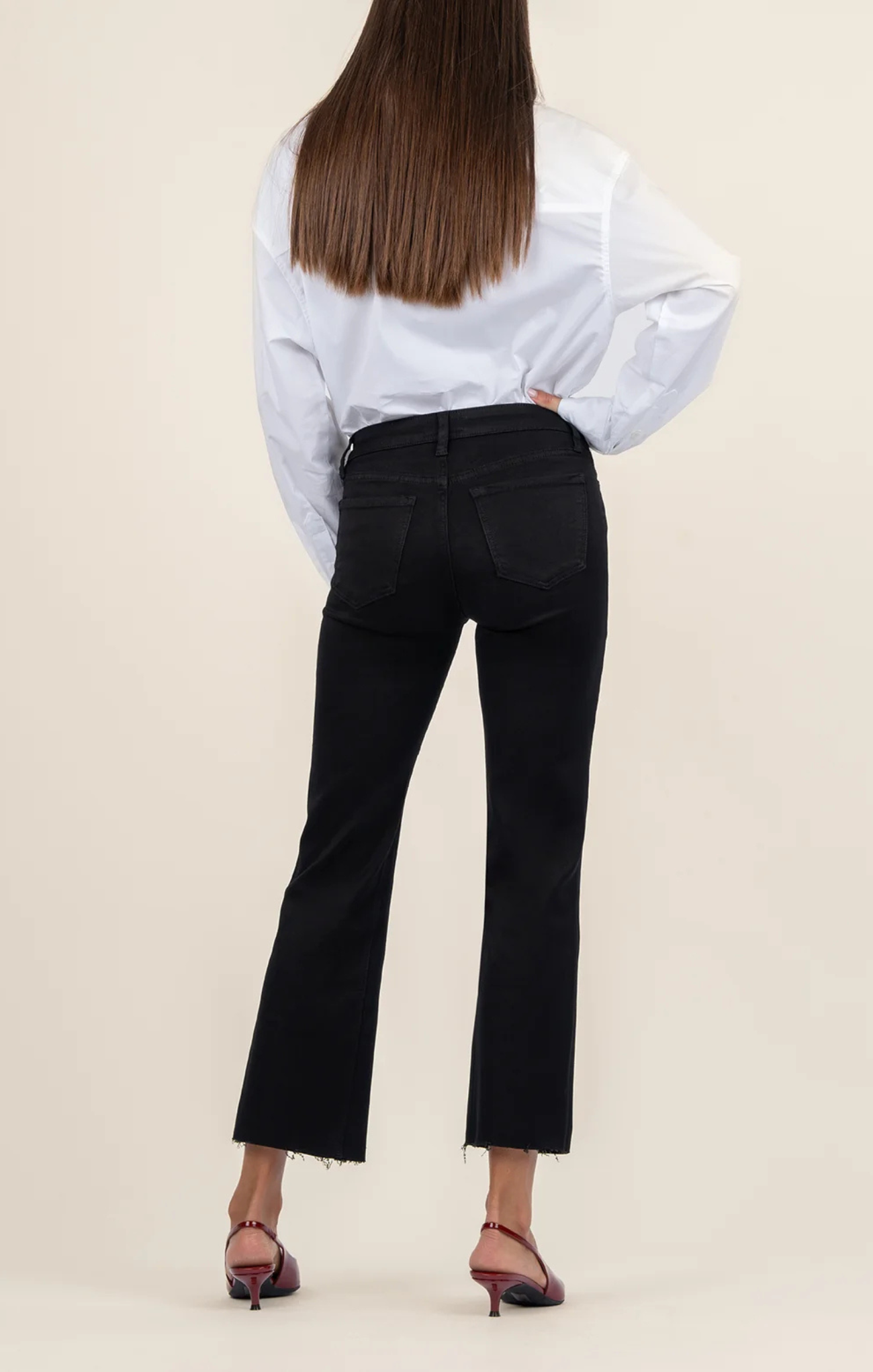 Person wearing a white blouse and black pants on a beige background