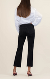 Person wearing a white blouse and black pants on a beige background