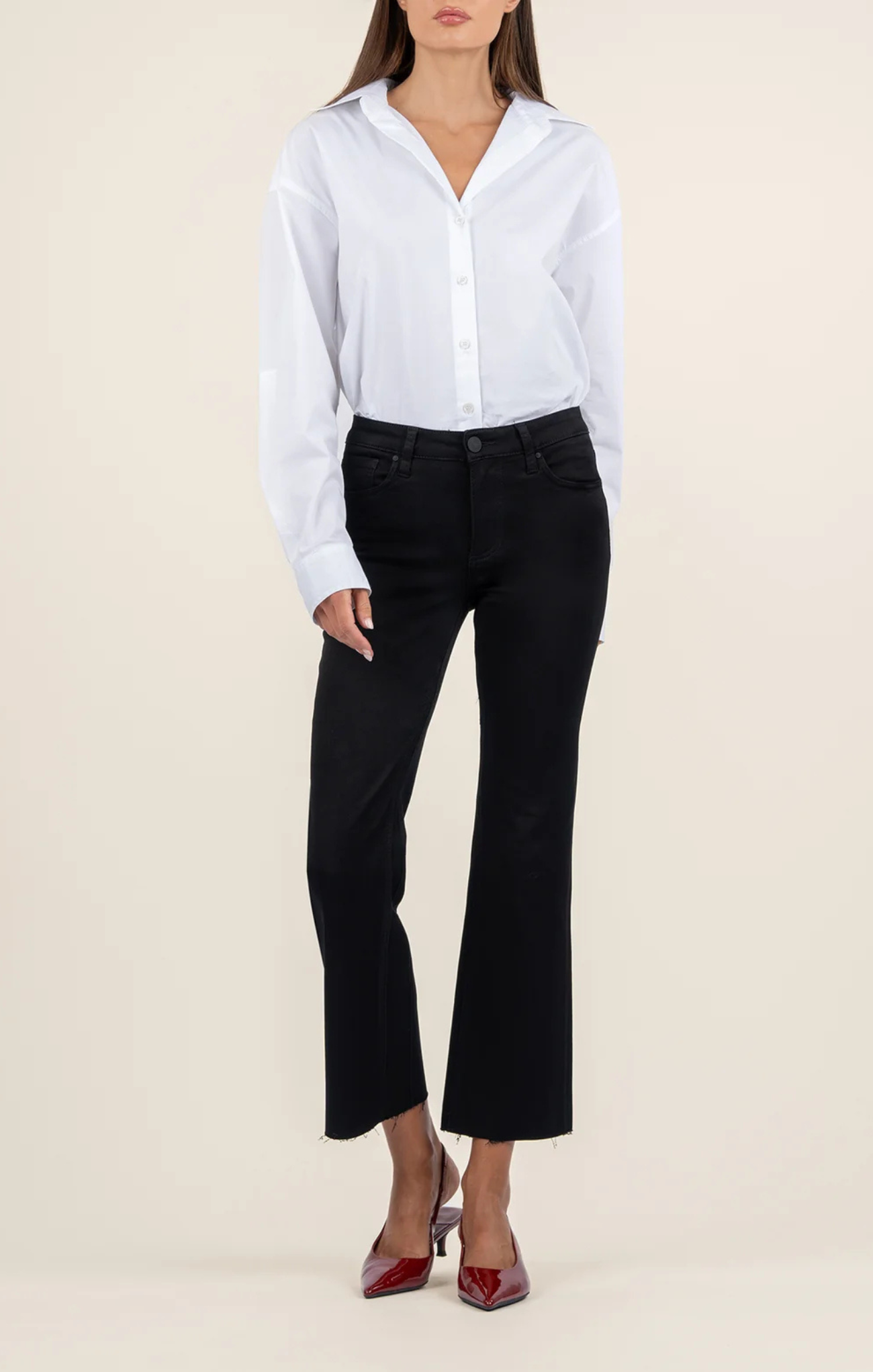 Person wearing a white button-up shirt and black pants on a beige background