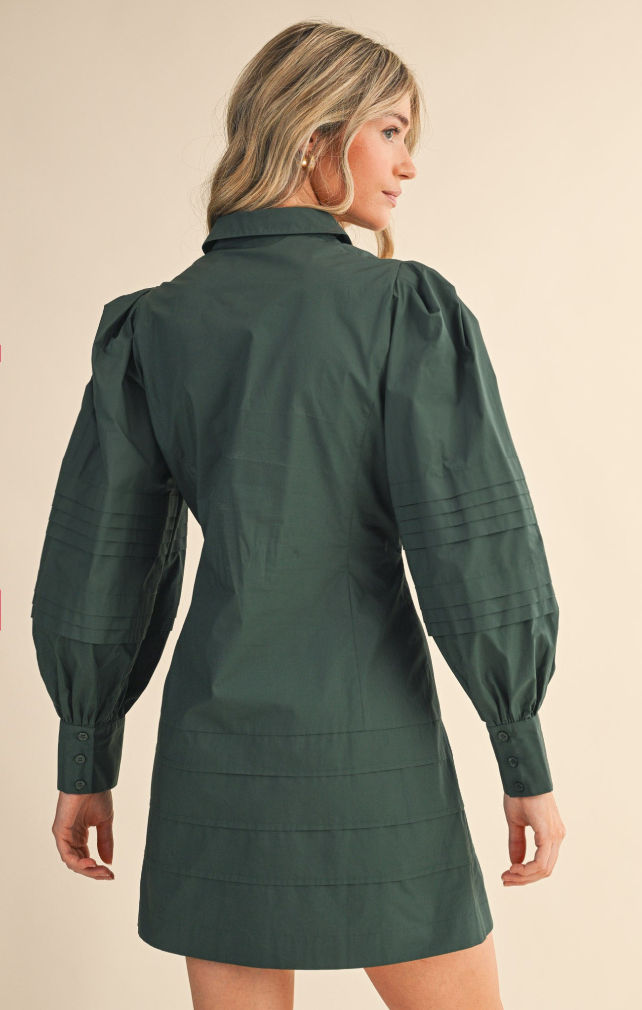 Woman wearing a green dress with puffed sleeves on a beige background