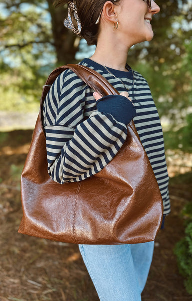 Woman carrying a brown leather bag outdoors