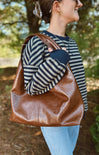 Woman carrying a brown leather bag outdoors