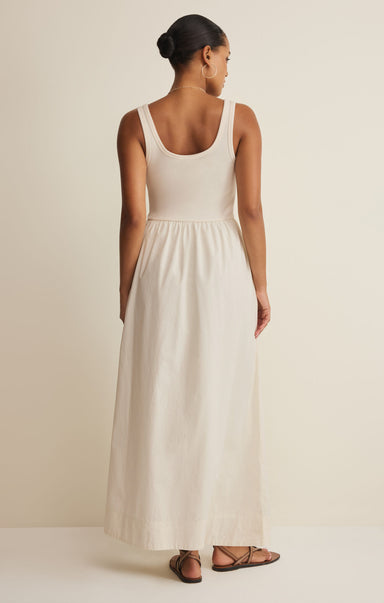 Woman wearing a white sleeveless dress against a plain background