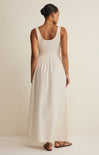 Woman wearing a white sleeveless dress against a plain background