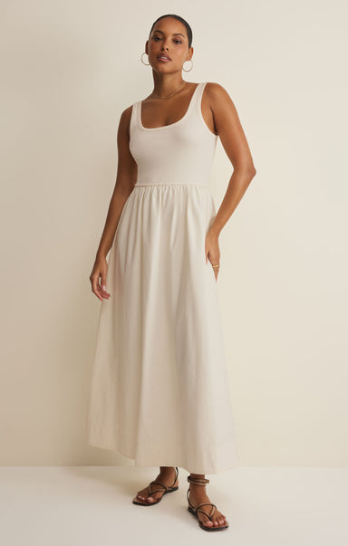 Woman wearing a white sleeveless dress against a plain background