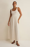 Woman wearing a white sleeveless dress against a plain background