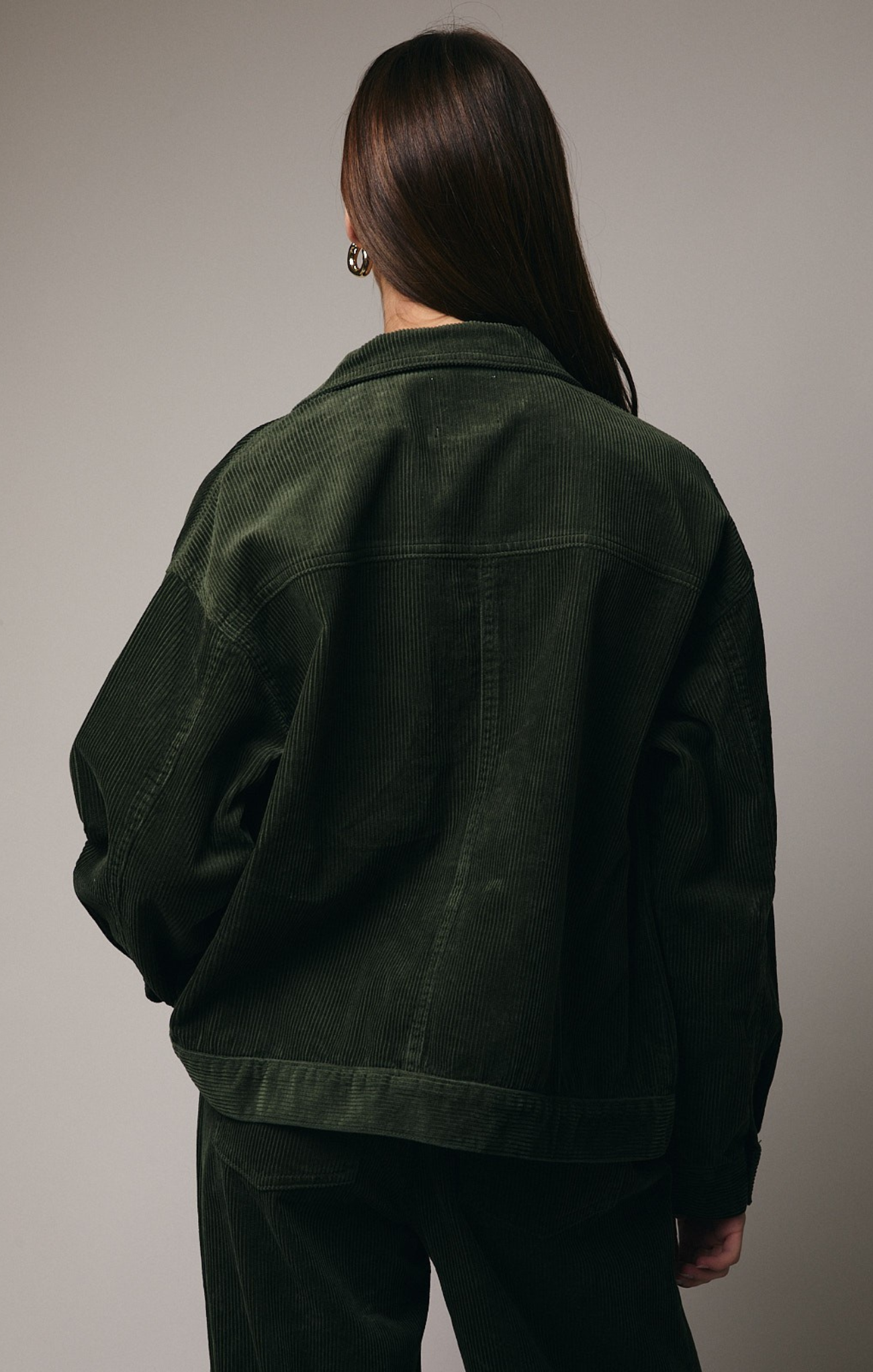 Person wearing a dark green jacket on a plain background