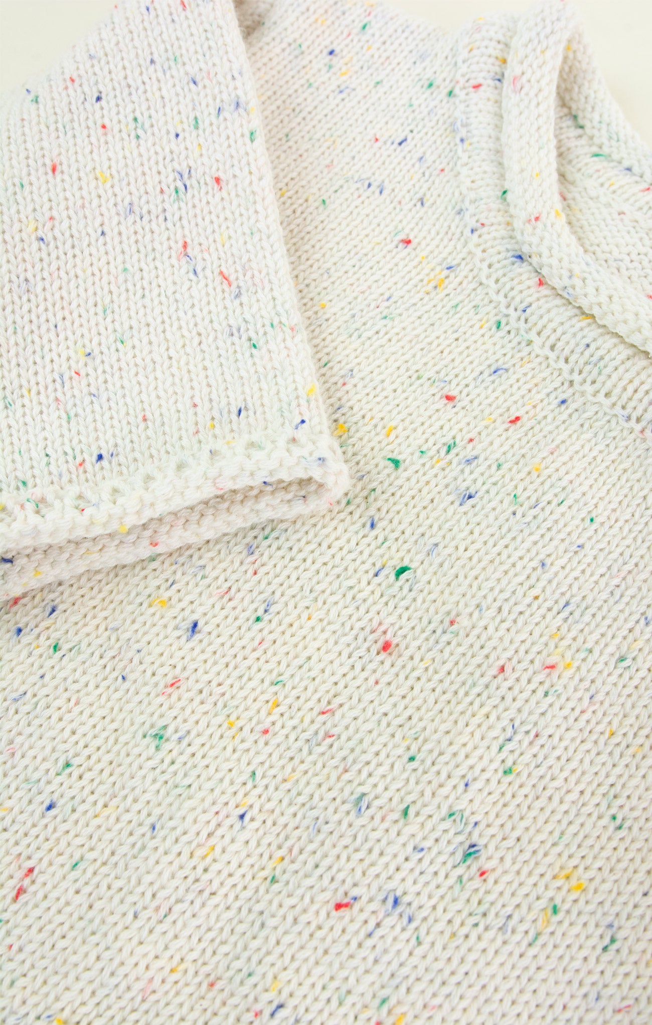 Close-up of a textured fabric with colorful speckles on a white background