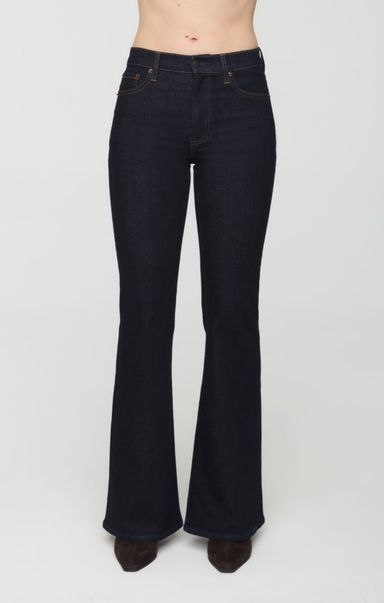 Dark wash flare jeans shown on a model from the waist down, featuring a classic five-pocket design and a flared leg, against a plain light gray background.