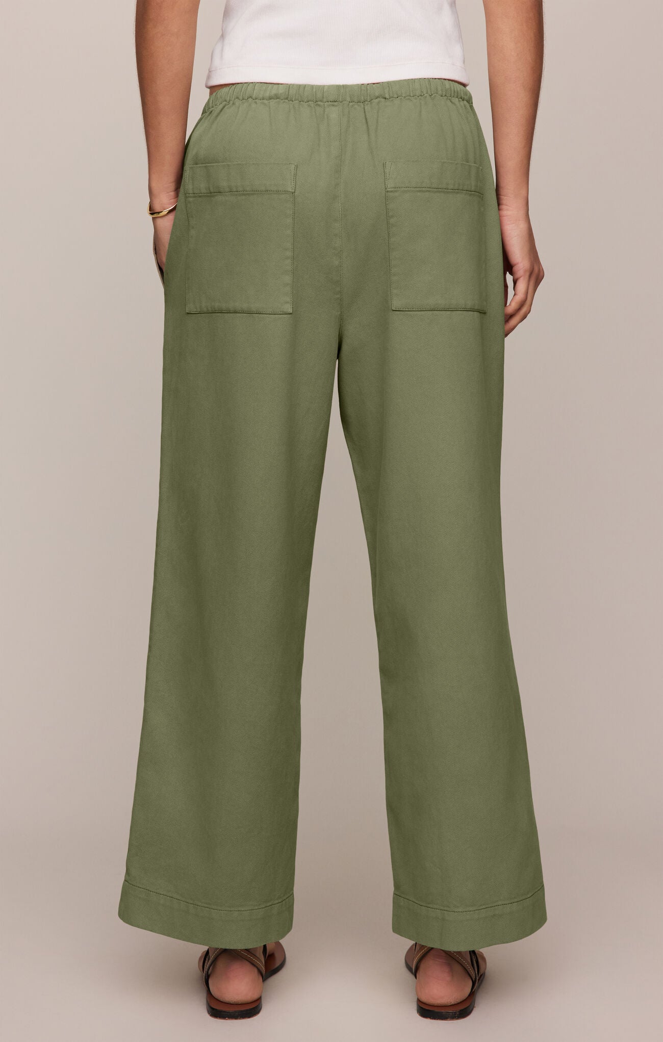Person wearing green wide-leg pants on a beige background