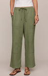 Person wearing olive green pants with a drawstring waist on a plain background