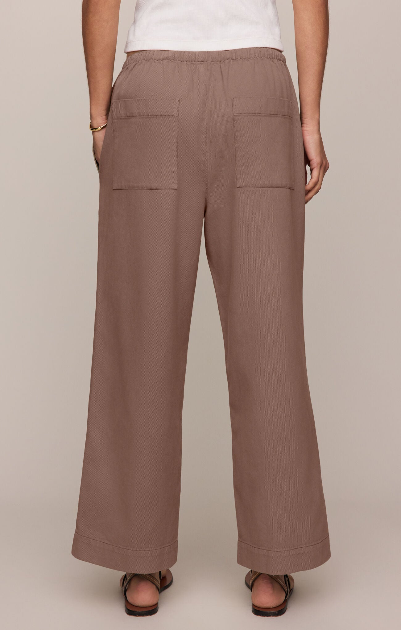 Brown wide-leg pants worn by a person on a beige background