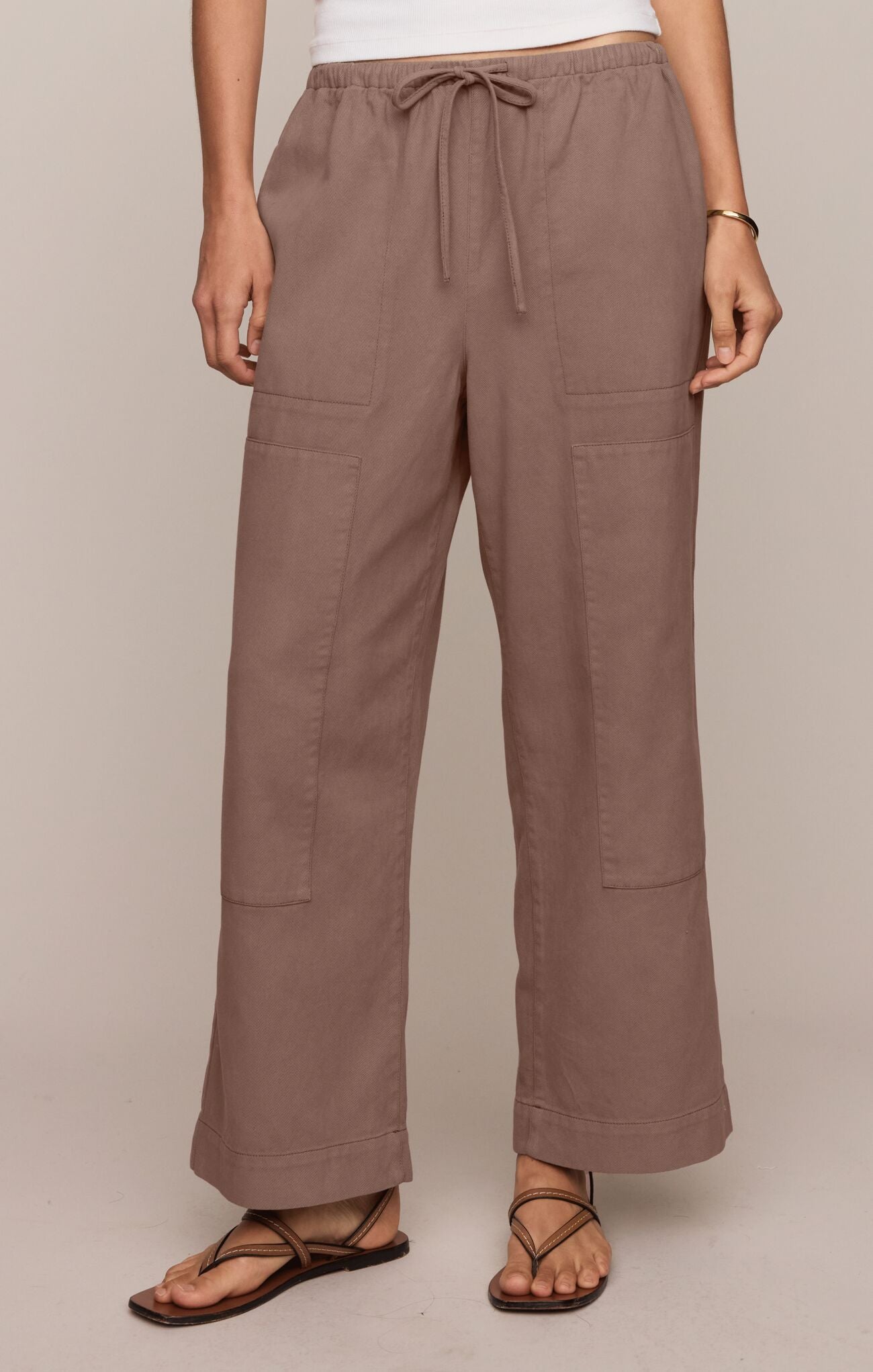 Brown pants worn by a person on a beige background