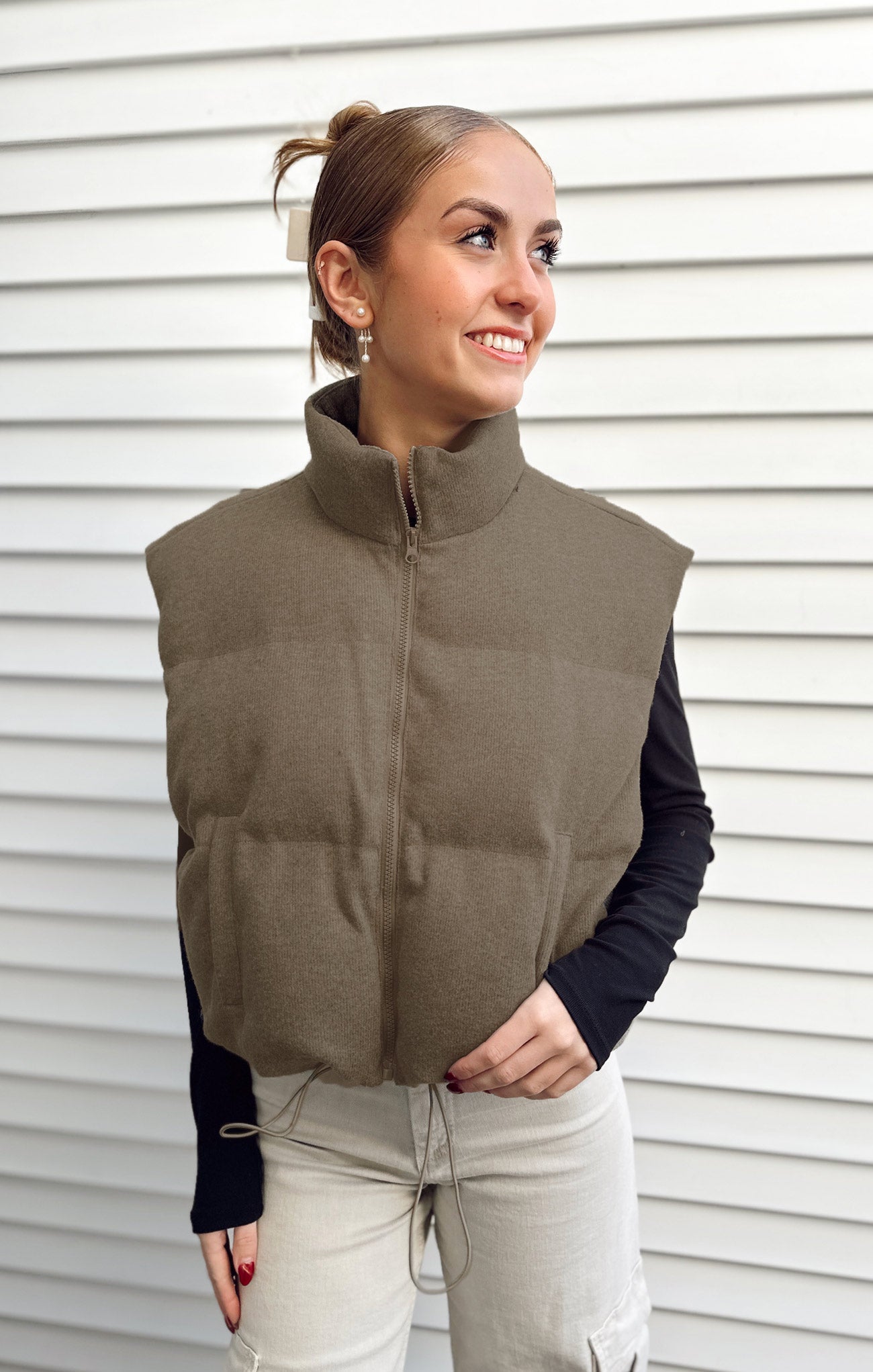 Woman wearing a brown puffer vest against a white background