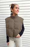 Woman wearing a brown puffer vest against a white background
