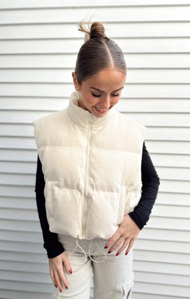 Woman wearing a white puffer vest against a white background