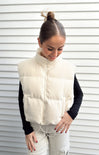 Woman wearing a white puffer vest against a white background