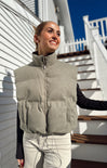 Woman wearing a gray puffer vest standing on a staircase with a white railing.