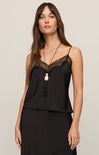 Woman wearing a black lace-trimmed top with a beige background