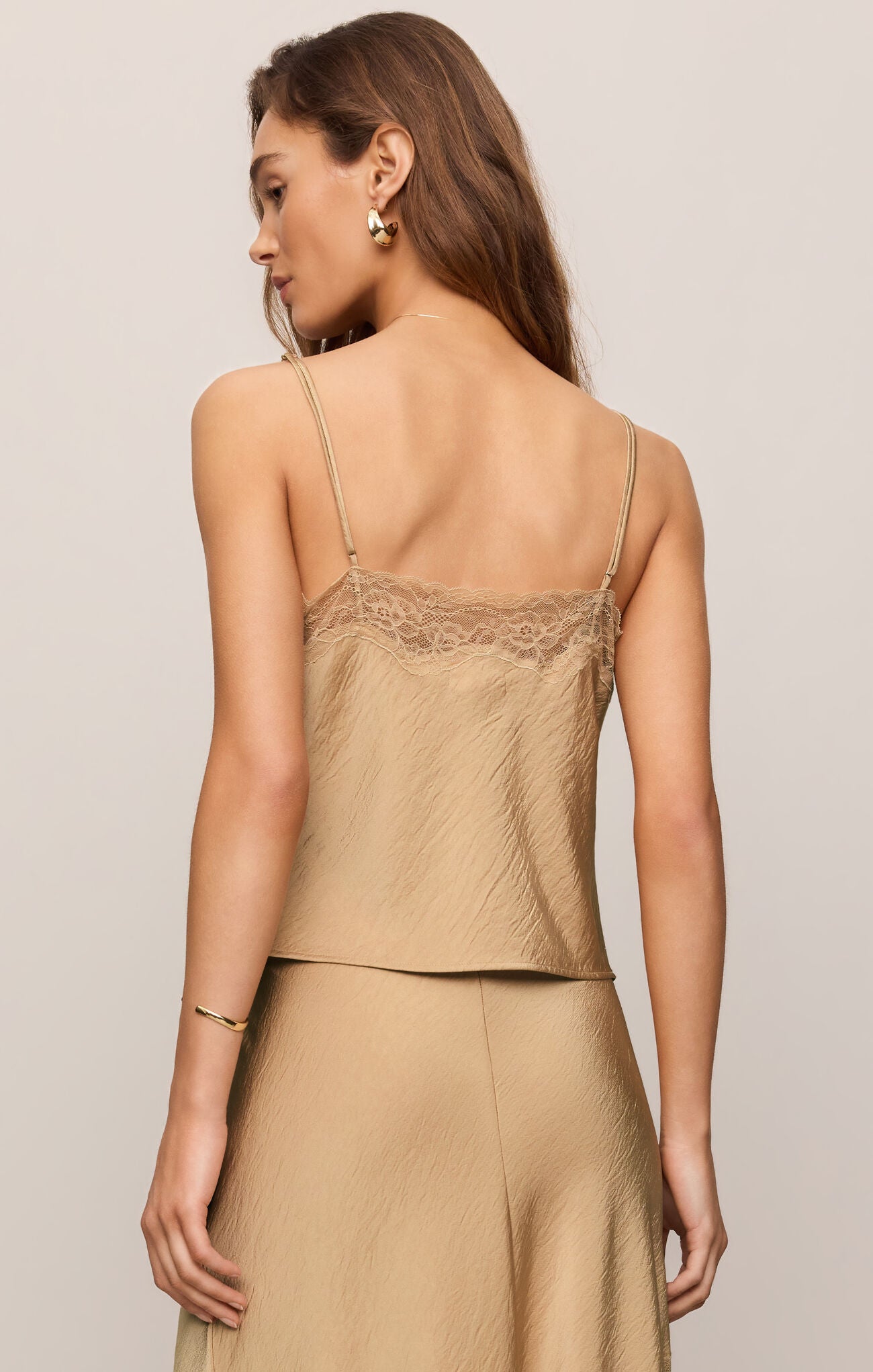Woman wearing a beige lace-trimmed top and skirt set on a neutral background