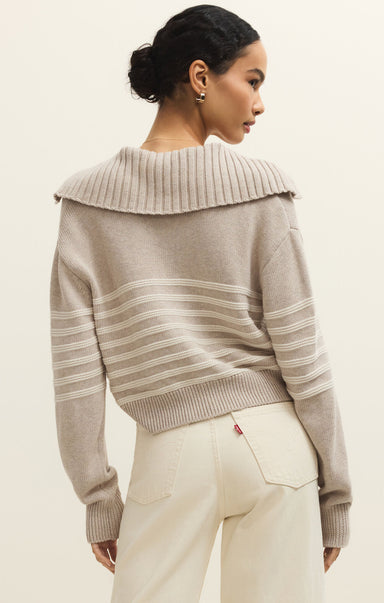 Woman wearing a beige sweater with a textured collar against a plain background